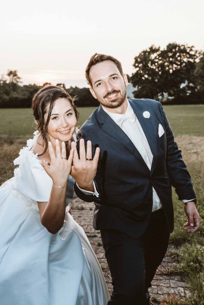 Braut und Bräutigam zeigen stolz ihre Eheringe bei einem fröhlichen Moment im Abendlicht in Böblingen.