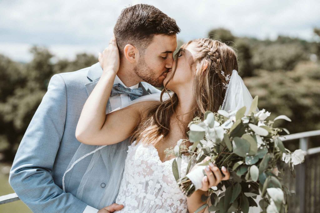 Kuss des Paares bei einem Shooting im Burggarten in Esslingen, mit sommerlicher Umgebung im Hintergrund.