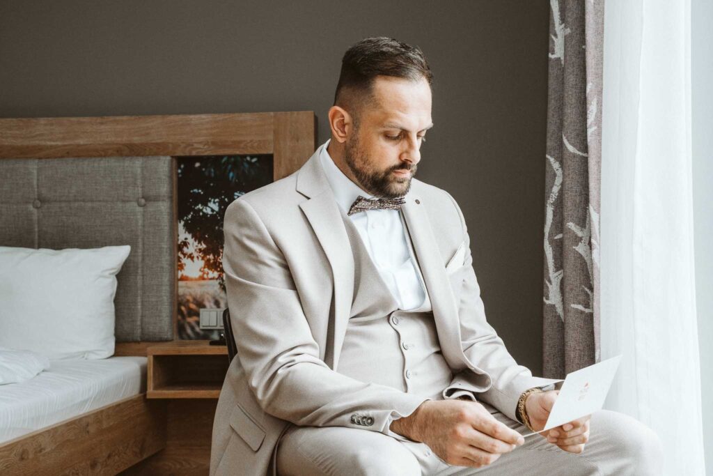 Bräutigam liest persönliche Nachricht bei den Getting-Ready-Momenten im Hotel in Breisach am Rhein.
