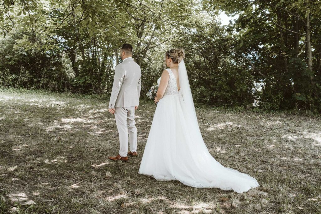 Braut steht hinter dem Bräutigam für den First Look in Breisach am Rhein, Hochzeitsfotograf Michael Schiltz.