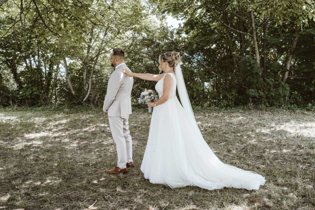 Braut tippt dem Bräutigam beim emotionalen First Look in Breisach am Rhein auf die Schulter, bevor er sich umdreht.