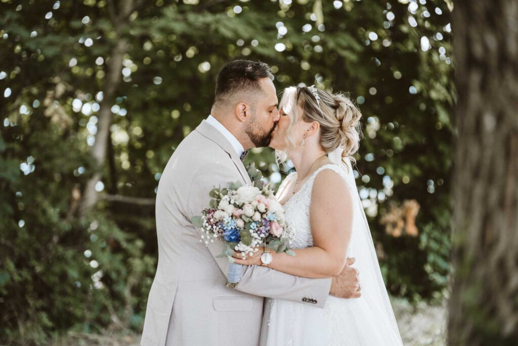 Brautpaar-Porträt im Weinberg in Breisach am Rhein, beide lächelnd in die Kamera, romantische Hochzeitsatmosphäre.