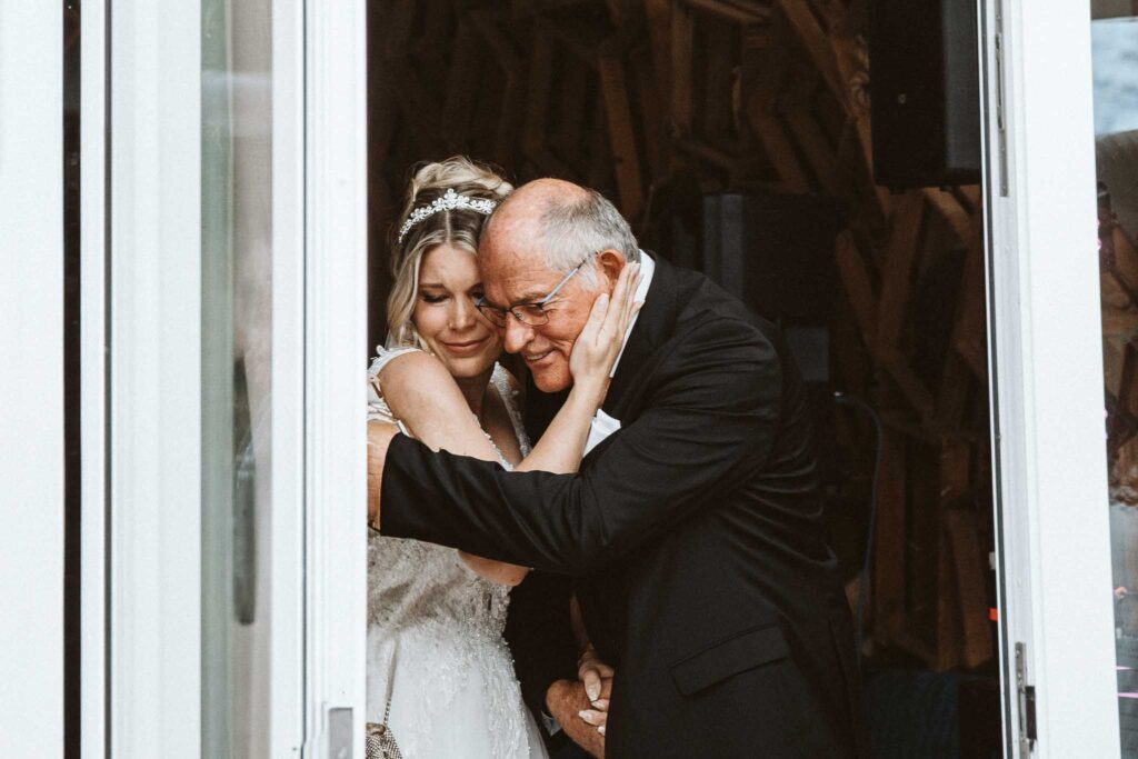 Braut umarmt ihren Vater emotional beim Einzug zur Hochzeit in Breisach am Rhein.