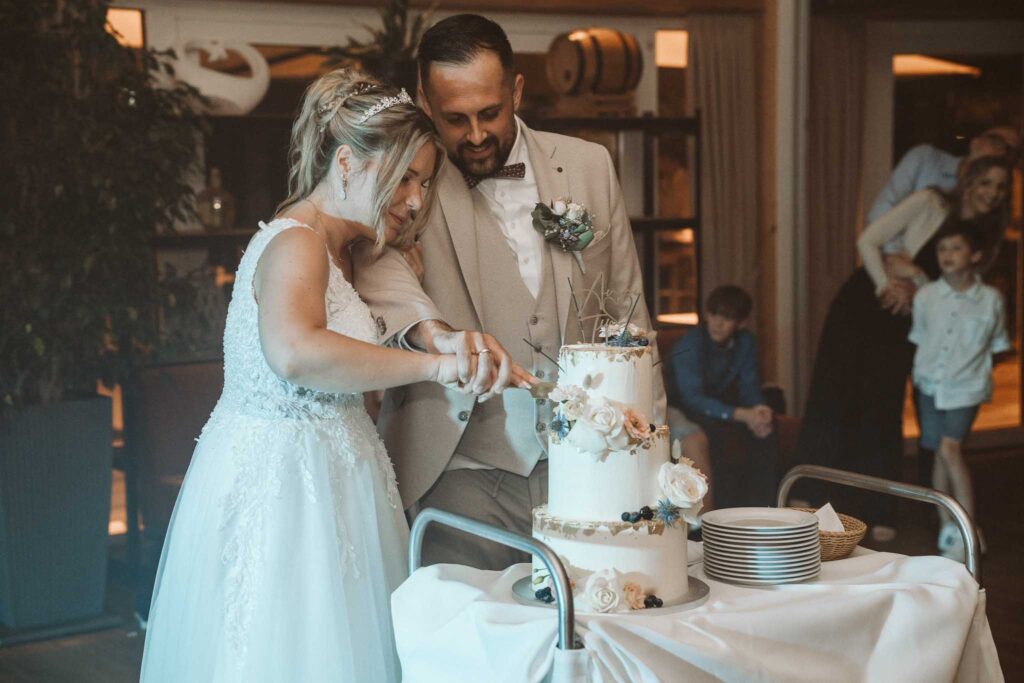 Braut und Bräutigam schneiden gemeinsam ihre Hochzeitstorte während der Feier in Breisach am Rhein an.