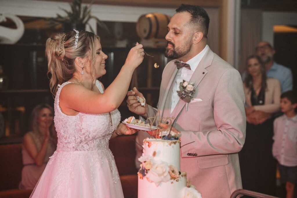 Brautpaar füttert sich bei der Hochzeit in Breisach am Rhein gegenseitig mit Hochzeitstorte.