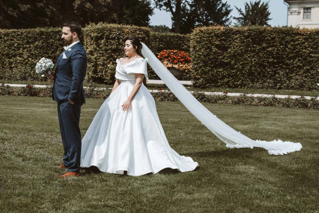 Aufgeregte Braut steht hinter dem Bräutigam im Schlossgarten Ludwigsburg und wartet gespannt auf den First Look.