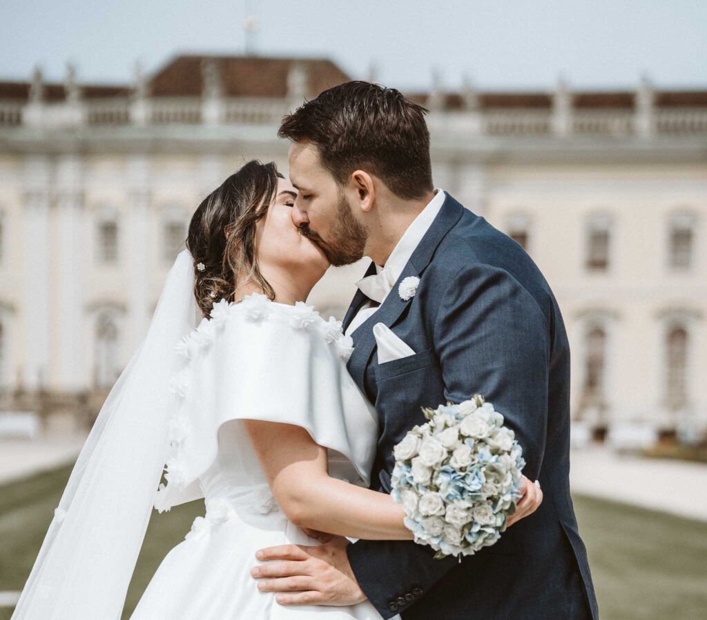 Brautpaar küsst sich vor der Kulisse des Schlosses in Ludwigsburg, inniger Moment während des Hochzeitsshootings.